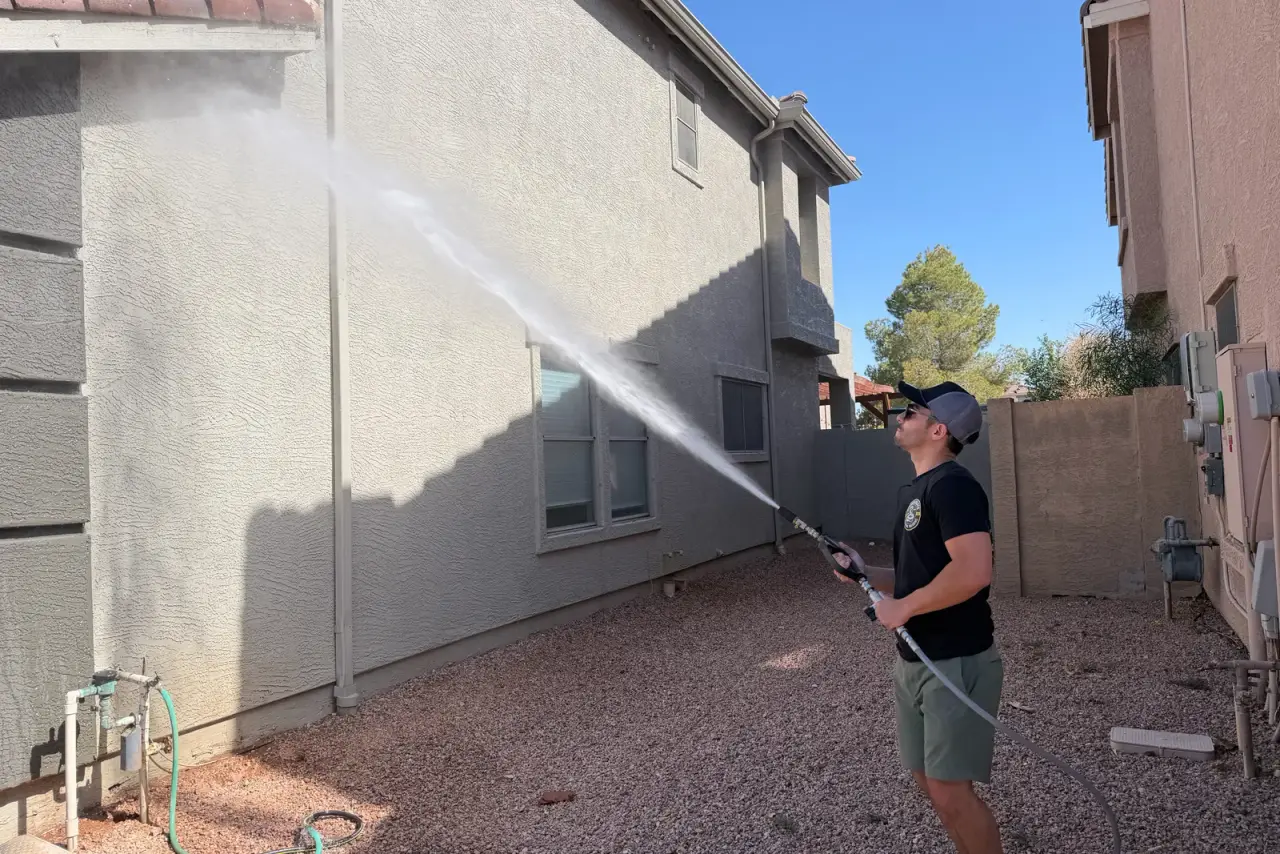 Diamondback technician soft washing a two-story Arizona stucco home exterior